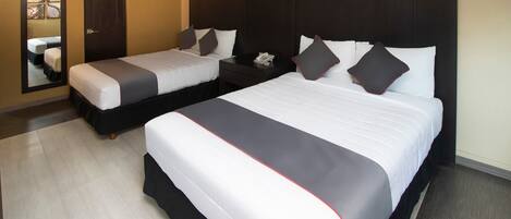 Quarto de hotel com duas camas, um espelho grande e cabeceira escura.