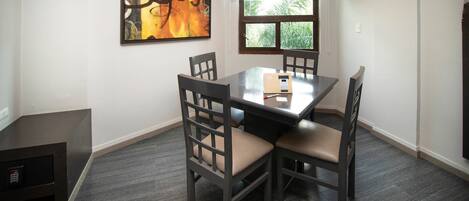 Un comedor con una mesa rectangular, cuatro sillas y un cuadro en la pared.