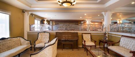 A grand room with a piano, ornate chairs, and a chandelier.