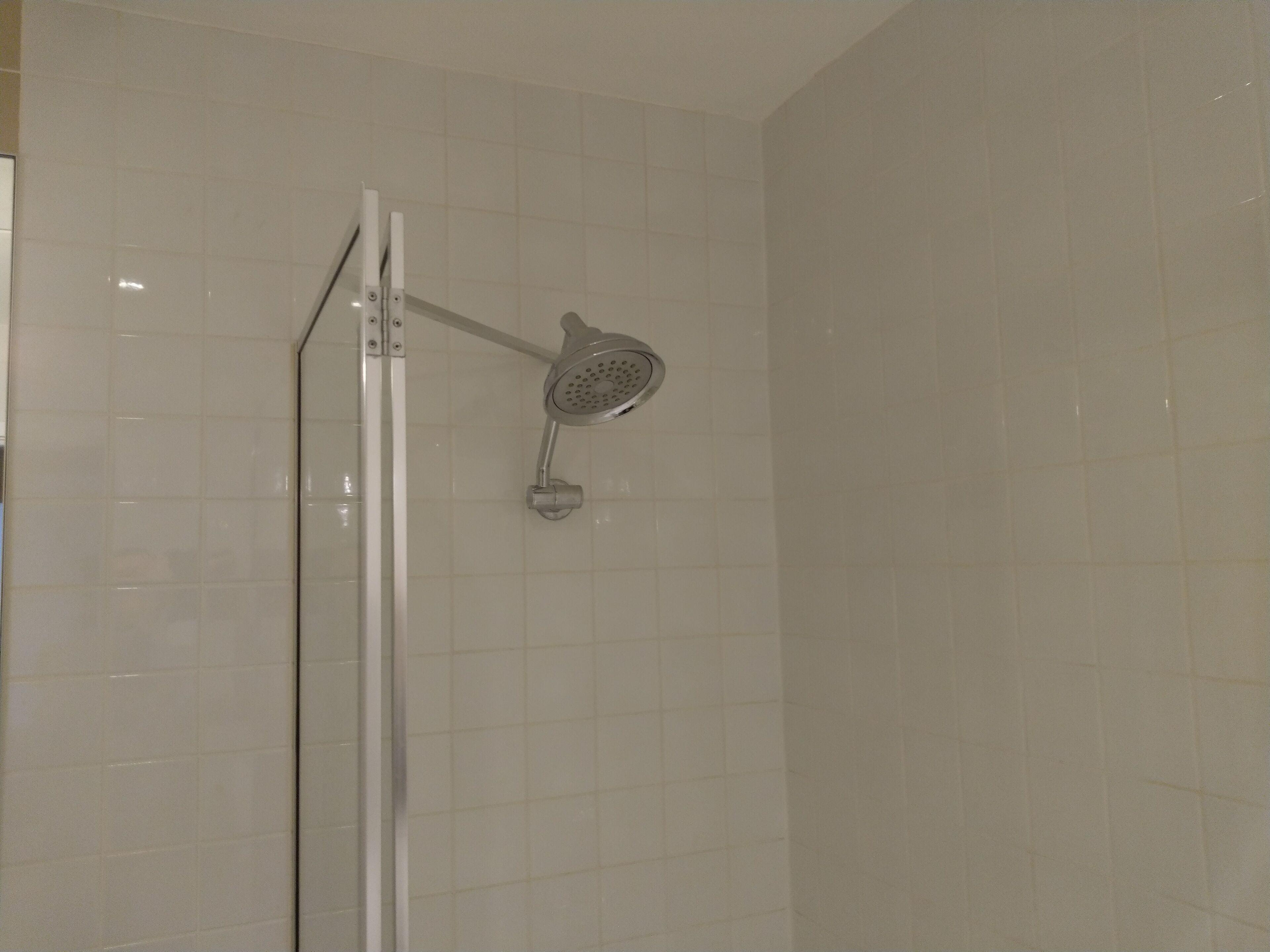 Une douche équipée d’un pommeau de douche mobile fixé au mur.