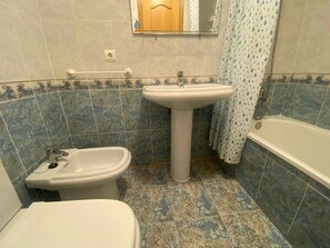 Ein Badezimmer mit Toilette, Bidet, Waschbecken und Badewanne.