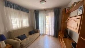 Ein Wohnzimmer mit einer Couch, einem TV-Schrank und einem Bücherregal.