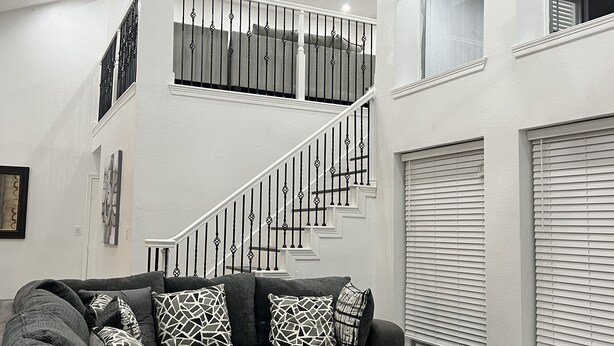 A modern living room with a gray sectional sofa, a coffee table, and a staircase with a railing.
