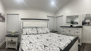 A bedroom with a bed, a nightstand, a dresser, and a mirror.