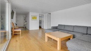 Un soggiorno moderno con un divano grigio, un tavolino in legno e un pavimento di legno.