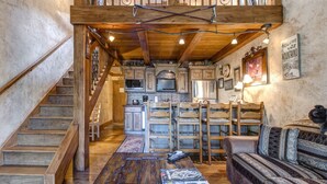 Ein rustikales Interieur mit einer Holztreppe, einer Küchenzeile und einer Sitzecke mit Sofa und Sesseln.