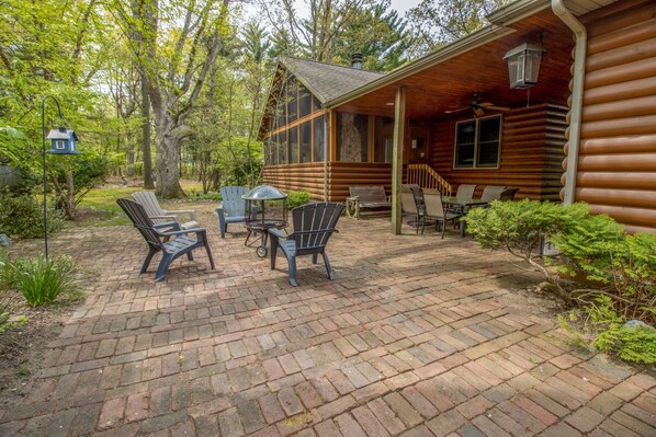 A log cabin with a patio area featuring outdoor seating and a small table.