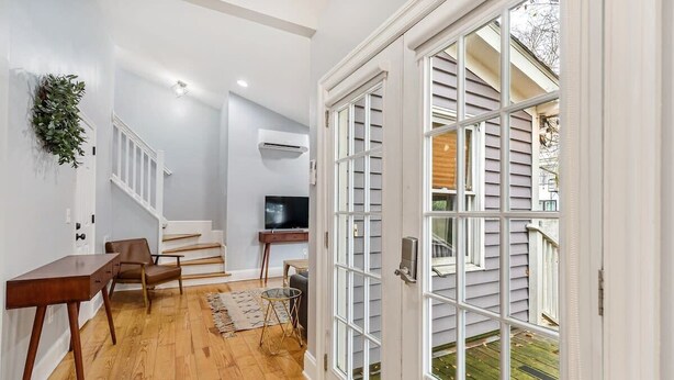A modern interior with a wooden floor, a dining area with a table and chairs, a staircase, and a large sliding glass door leading to an outdoor area. - Spacious and Quiet One Block off King Street (Charleston)