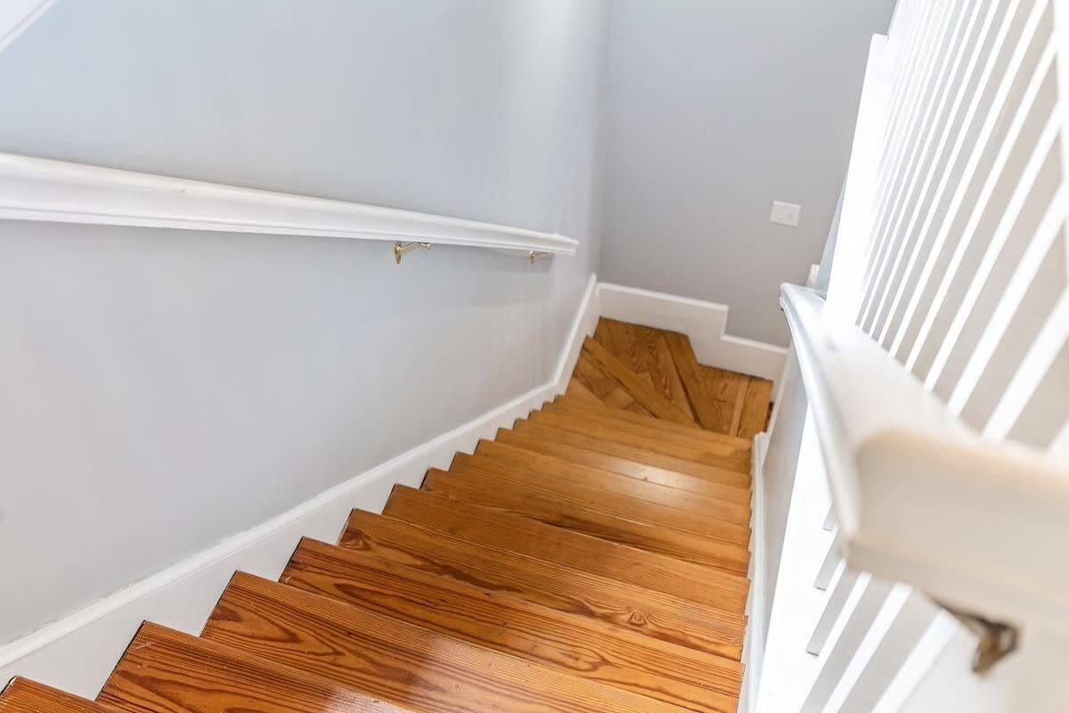 A wooden staircase with white railings and a light-colored wall.