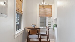 A small dining area with a round table and two chairs, a window with blinds, and a hanging light fixture. - Spacious and Quiet One Block off King Street (Charleston)