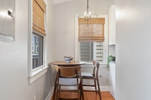 Cozy dining area with a round table and two chairs, featuring a pendant light and a potted plant.