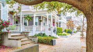 A row of townhouses with front porches, steps leading up to the entrance, and hanging flower baskets. - Spacious and Quiet One Block off King Street (Charleston)