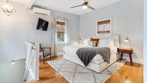 A bedroom with a bed, a ceiling fan, a TV, a window with blinds, a wooden floor, and a radiator. - Spacious and Quiet One Block off King Street (Charleston)