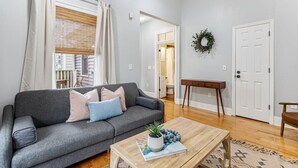 A living room with a grey sofa, a wooden coffee table, and a view of a hallway. - Spacious and Quiet One Block off King Street (Charleston)