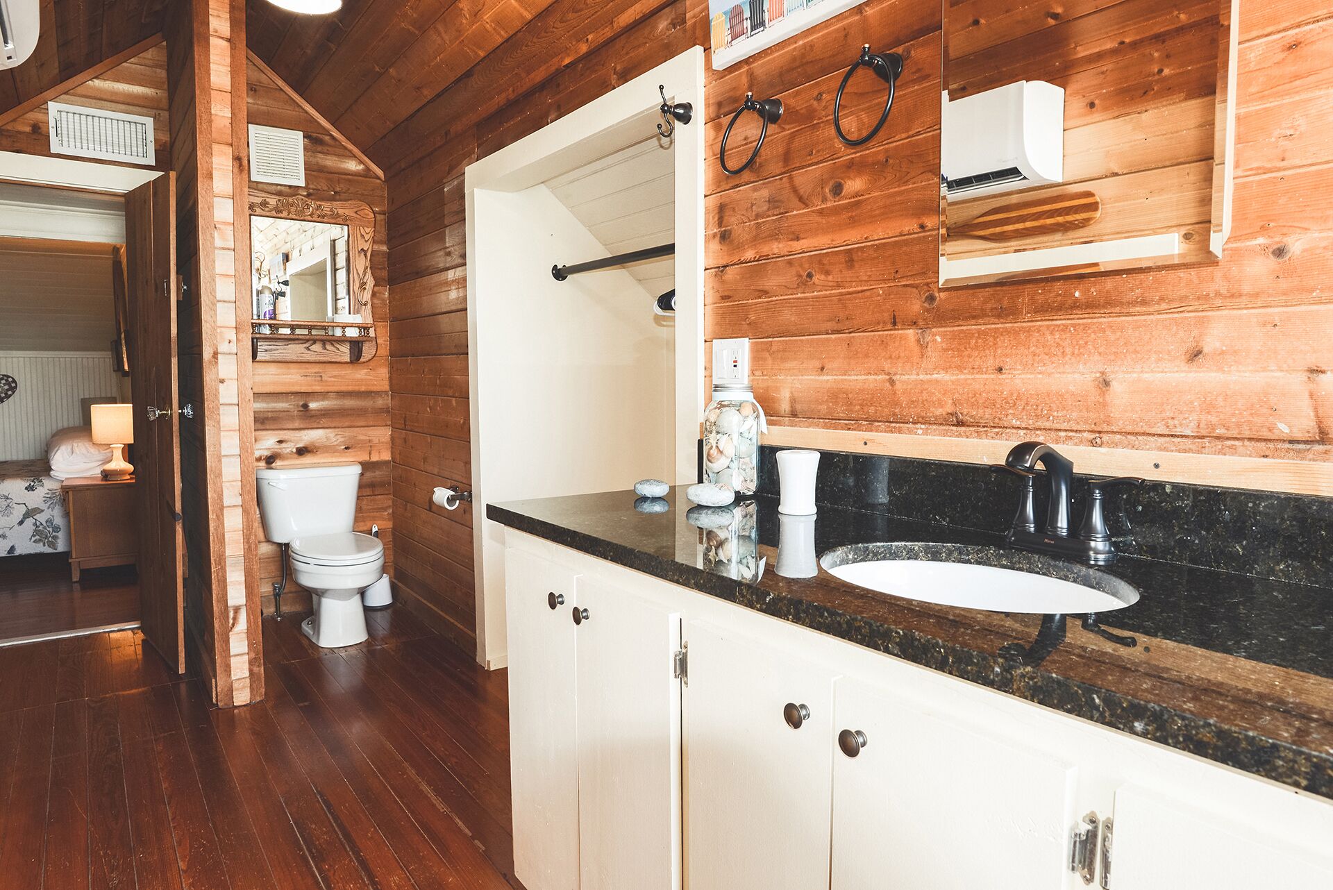 Interior em madeira com banheiro, incluindo vaso sanitário, pia e espelho.