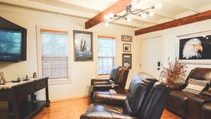 A living room with leather sofas, a wooden coffee table, and a television on the wall.