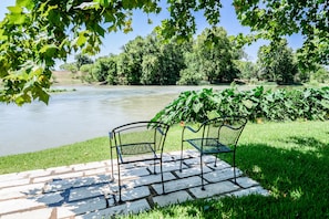 Un parc au bord de la rivière, avec deux chaises en métal disposées sur un sentier de pierre.