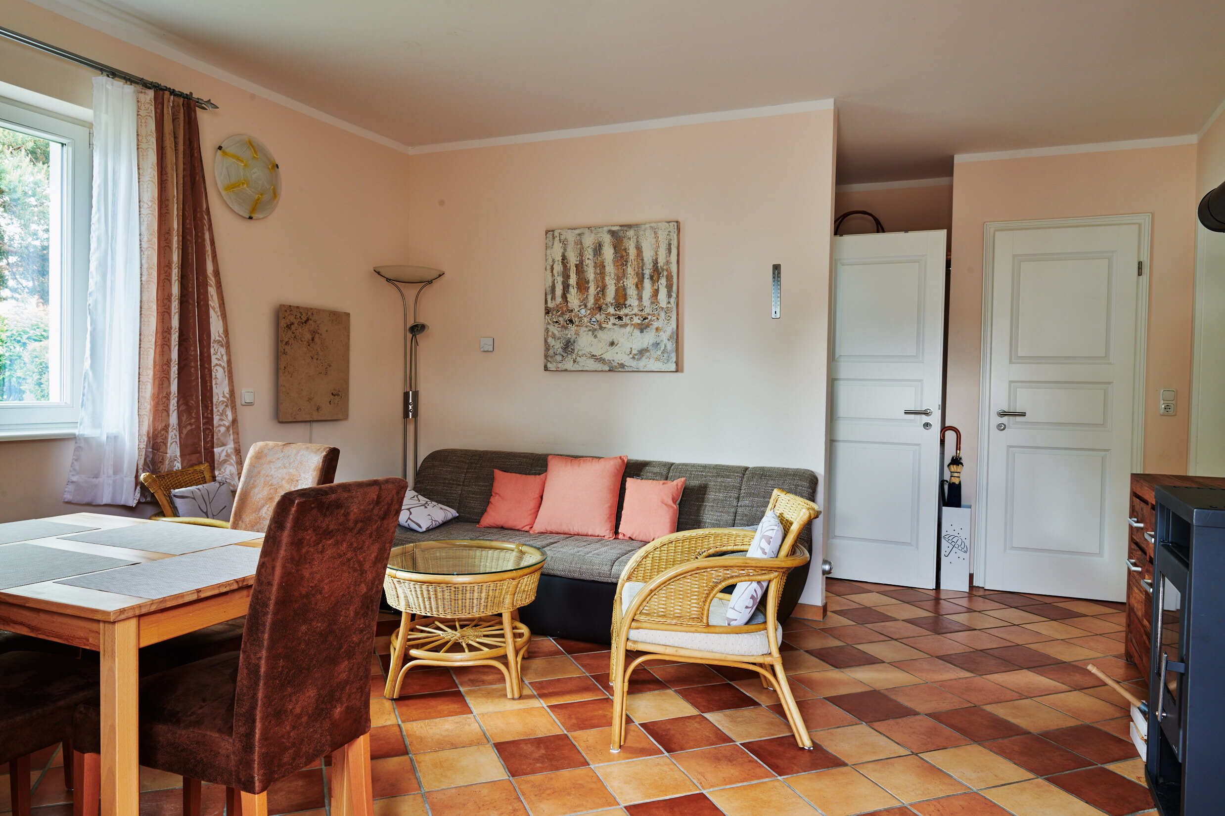 Una sala acogedora con sofá, sillas, una mesa de comedor y un amplio ventanal con cortinas.