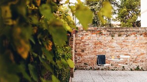 A brick wall with a small table and two chairs, a window, and a door.