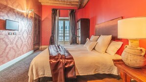 Camera d'albergo con un letto grande, una testiera in legno, una televisione e un vaso su un comodino.