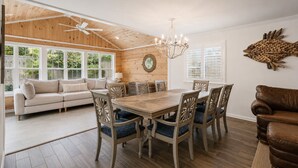 A spacious living room with a wooden ceiling, a dining area with a large table and chairs, and a cozy seating area with a sofa.