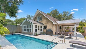 A residential property with a swimming pool, a covered patio area, and a detached garage.