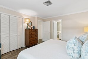 A bedroom with a bed, dresser, and closet.