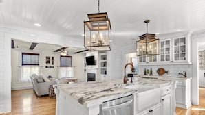 A spacious kitchen with white cabinetry, a marble countertop island, and pendant lighting. - Historic home in seaside village of Swansboro w/ private beach parking  (Swansboro)
