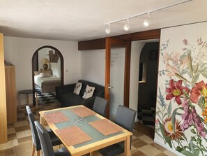 Un comedor con una mesa dispuesta para cuatro personas, un sofá y un espejo.
