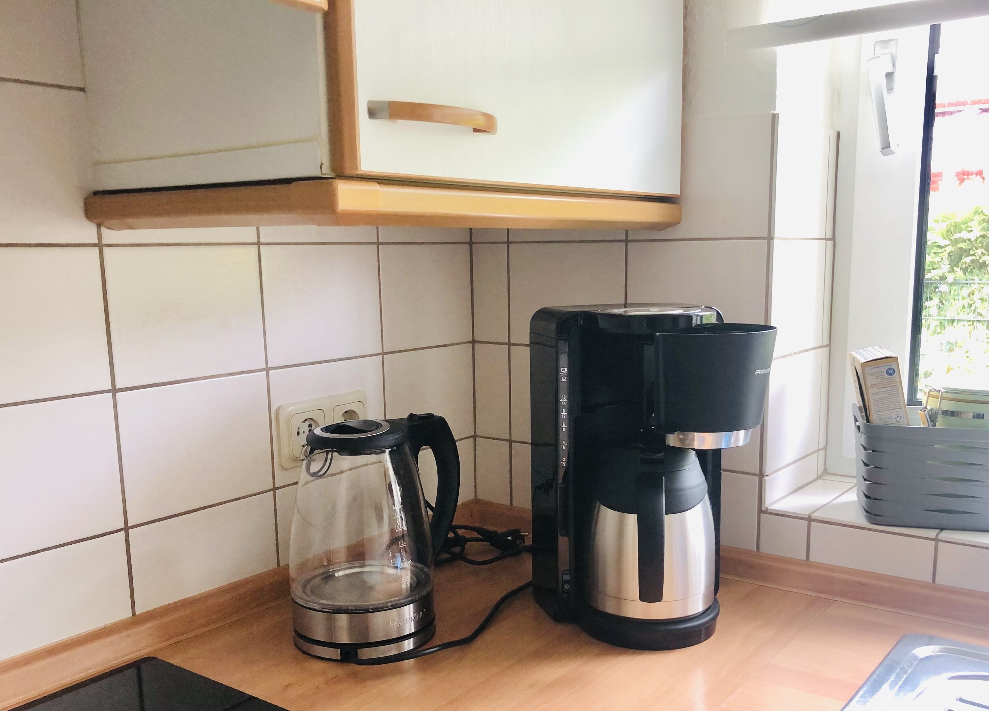 Une cuisine équipée d’une machine à café et d’une verseuse en verre posée sur le plan de travail.