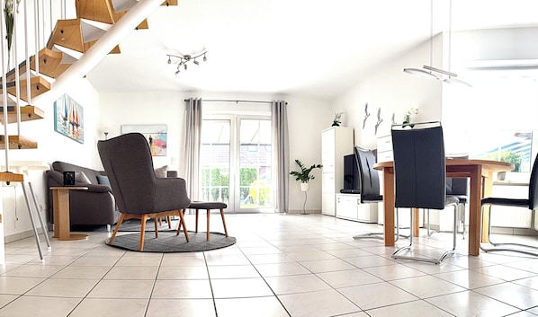 A spacious living area with a modern chair, a dining table, and a staircase.