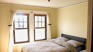 Un dormitorio con cama, ventana con cortinas y cabecero.