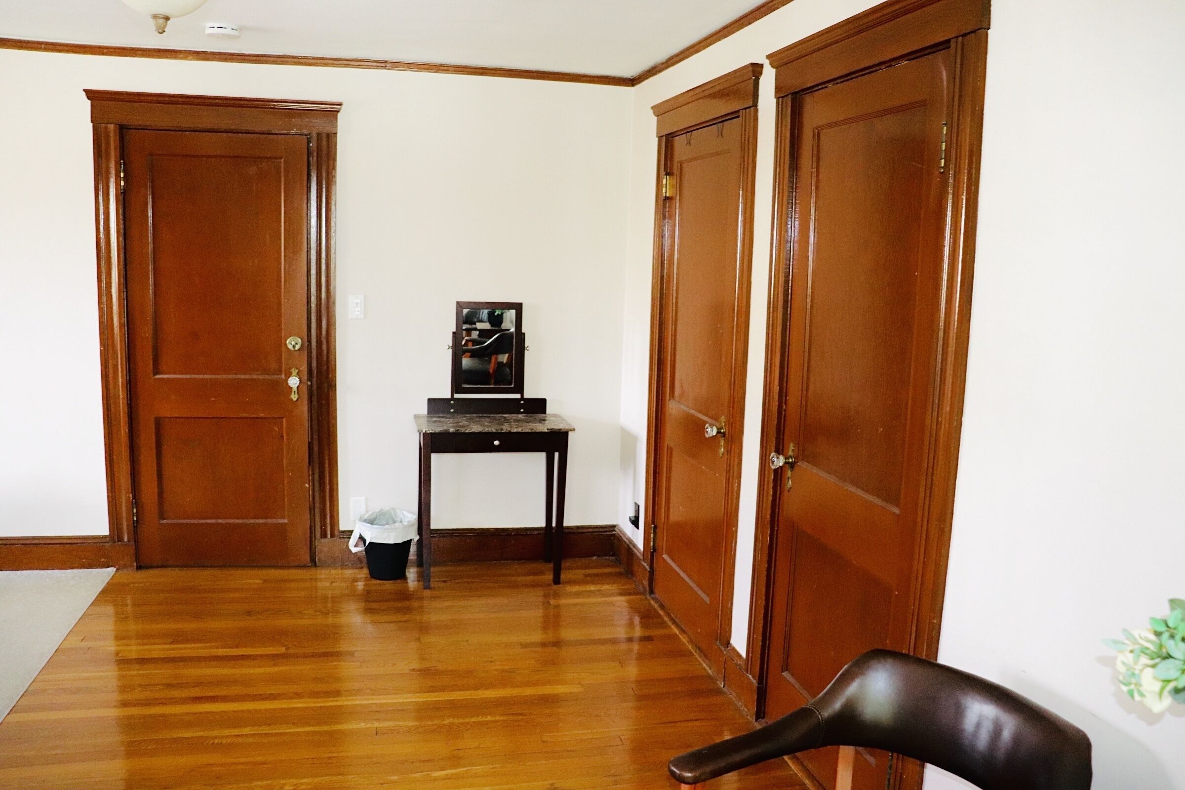 Une pièce avec un plancher en bois, un bureau avec un ordinateur et deux portes en bois.