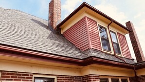 A corner of a building with a red and beige exterior, a brick chimney, and a window with a brown gutter. - The Sunset Room at TPH - Boston (Boston)
