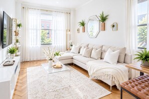 A modern living room with a sectional sofa, a coffee table, and decorative plants.