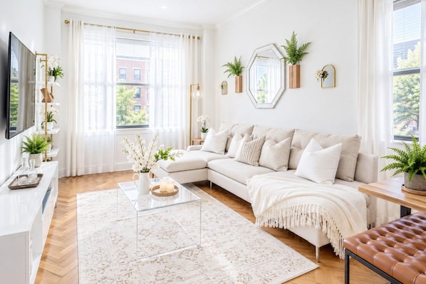 A modern living room with a sectional sofa, a coffee table, and decorative plants.