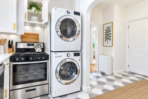 A compact kitchen with a stove, oven, and stacked washer-dryer unit. - Brooklyn Brydge · Private 3BR · Free Parking (Brooklyn)