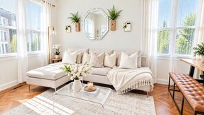A living room with a sofa, coffee table, and a bench. There are plants on the walls and a window with blinds. - Brooklyn Brydge · Private 3BR · Free Parking (Brooklyn)