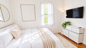 A bedroom with a bed, a bedside table, a dresser, a TV, and a window with curtains. - Brooklyn Brydge · Private 3BR · Free Parking (Brooklyn)