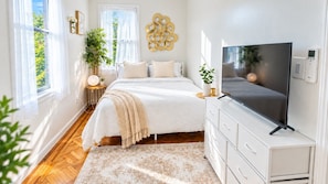 A bedroom with a bed, bedside table, lamp, TV, and a wall-mounted decorative piece.