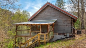 Une cabane rustique dotée d’une terrasse en bois et d’un toit en métal.