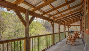 A wooden deck with a metal roof, surrounded by trees. - Angler's Ridge Log Cabin - Authentic Log Cabin (Sevierville)