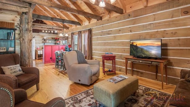 Un intérieur de chalet chaleureux avec un plafond en bois, un téléviseur et un coin repas.