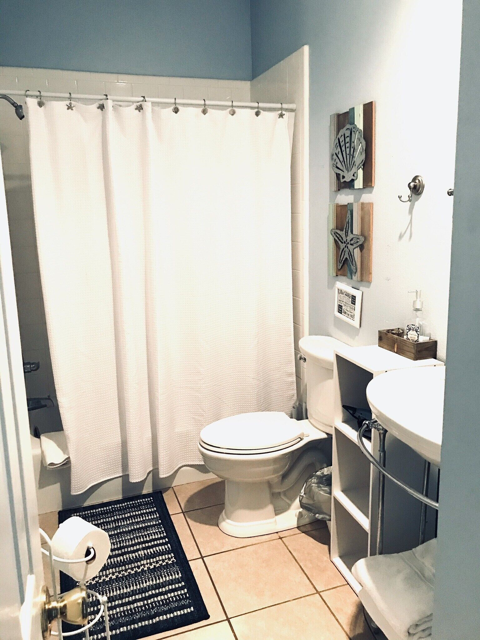 Un baño con inodoro, lavamanos y cortina de ducha.