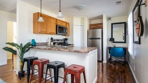 Una cocina moderna con armarios de madera, microondas integrado y una isla central con taburetes.