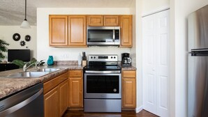 Una cocina con armarios de madera, un microondas de acero inoxidable, una estufa y un lavavajillas.