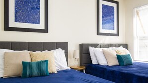 A hotel room with two beds, each with a blue bedspread and multiple pillows. There are framed pictures on the wall above the beds. - Sanitized Spacious East Nash Apt!  Walk to Top Restaurants! (Nashville)