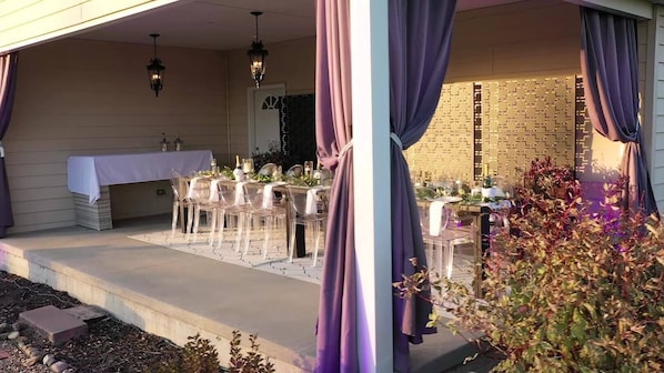 Enjoy a formal dining experience in this beautifully set outdoor space with a long table and elegant seating.