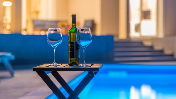 A poolside table with two wine glasses and a bottle of wine, set against a pool and a building with steps in the background. - Pet friendly home in Vrh (Vrh)