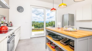 A modern kitchen with a large window, a red kettle, and a variety of cookware on shelves. - Pet friendly home in Vrh (Vrh)